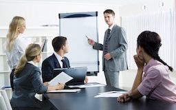 Image of smart business people looking at their leader while he explaining something on whiteboard during seminar